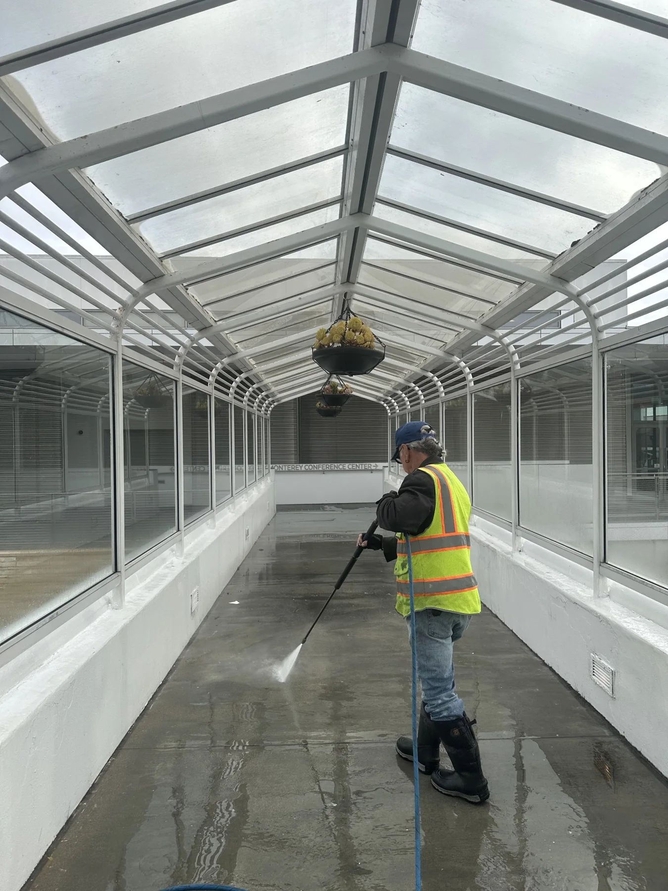 Team member cleaning inside a glass-covered walkway