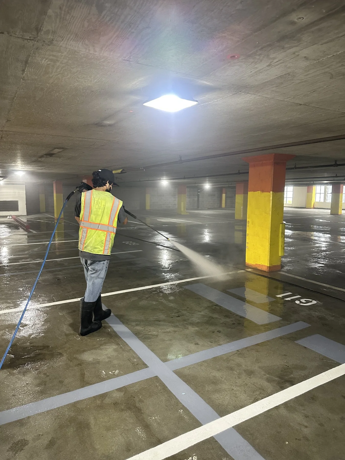 Team member pressure washing a parking garage